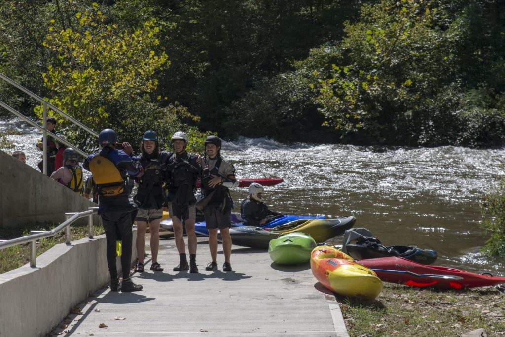 Kayakers standing next to river taking pictures