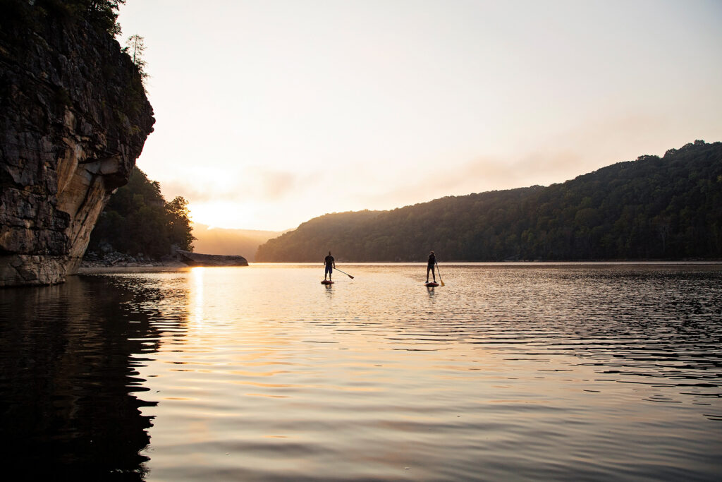 Two paddle boarders along a river, silhouetted by a sunset and mountains. Photo by West Virginia Department of Tourism