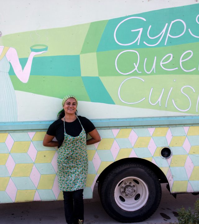 Gypsy Queen Cuisine owner in front of her truck, smiling.